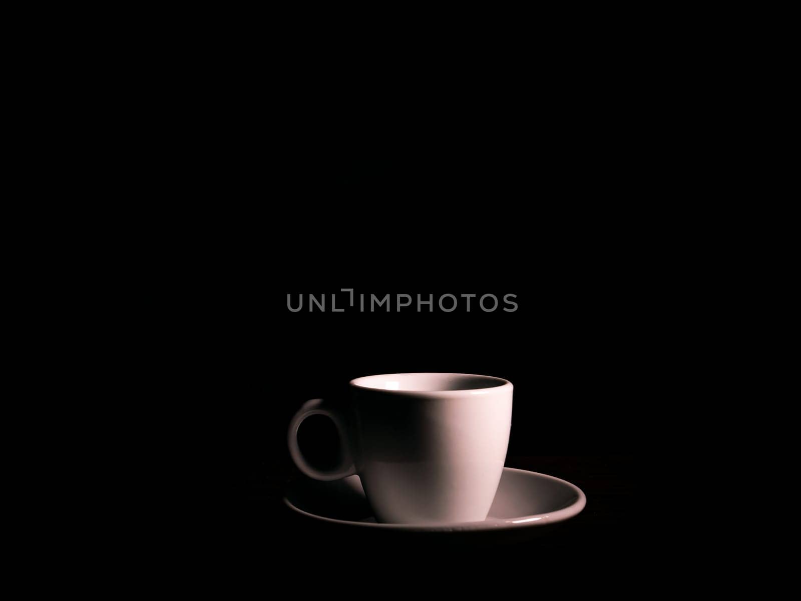 White ceramic coffee cup with saucer on a black background. Coffee cup and saucer. White ceramic dishes. Hot drinks. Kitchenware. Preparing a hot drink. Hot tea. Background image. Poster. Showcase.
