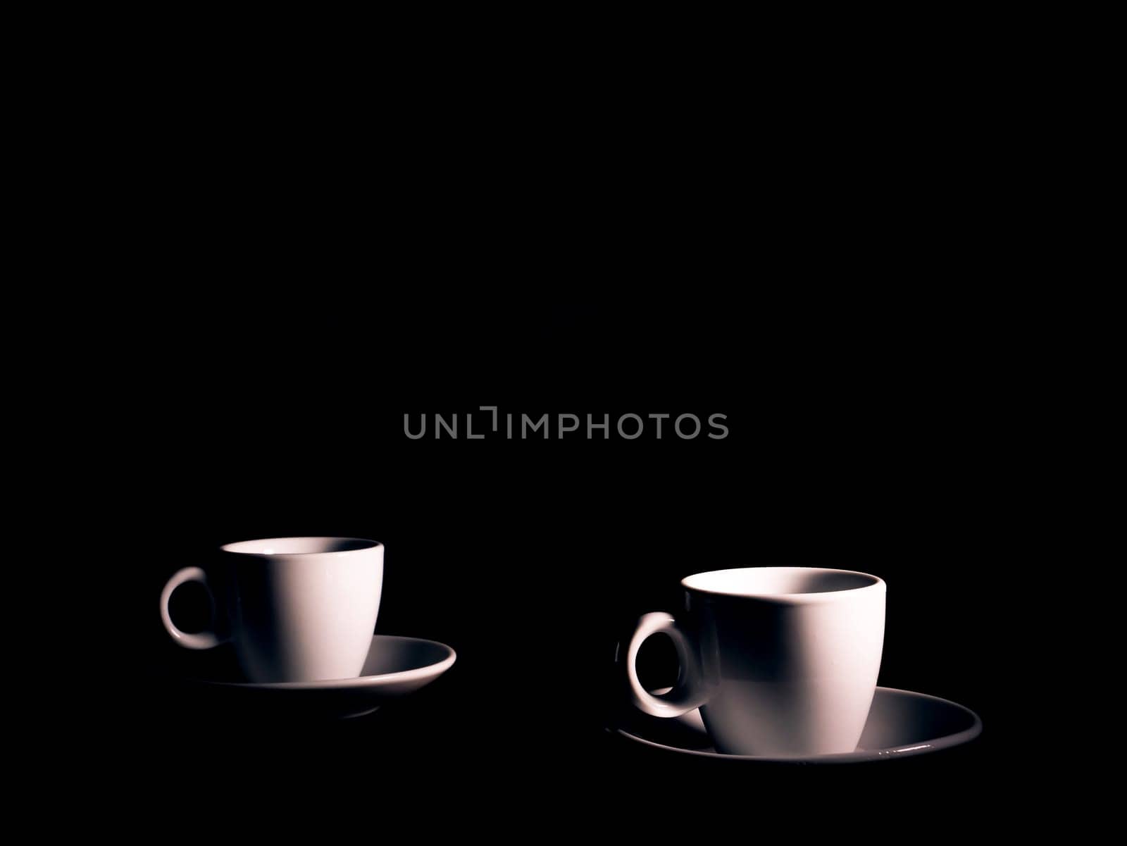 White ceramic coffee cup with saucer on a black background. Coffee cup and saucer. White ceramic dishes. Hot drinks. Kitchenware. Preparing a hot drink. Hot tea. Background image. Poster. Showcase.