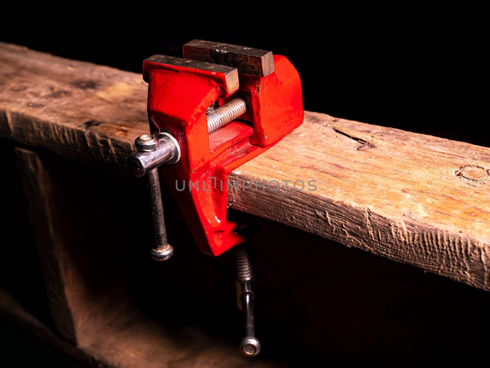 Locksmiths tool metal vise fixed on a wooden table. Iron vise equipment mechanic. Working tool of the master. Customer Service. Background image. Place for text. Workshop equipment.