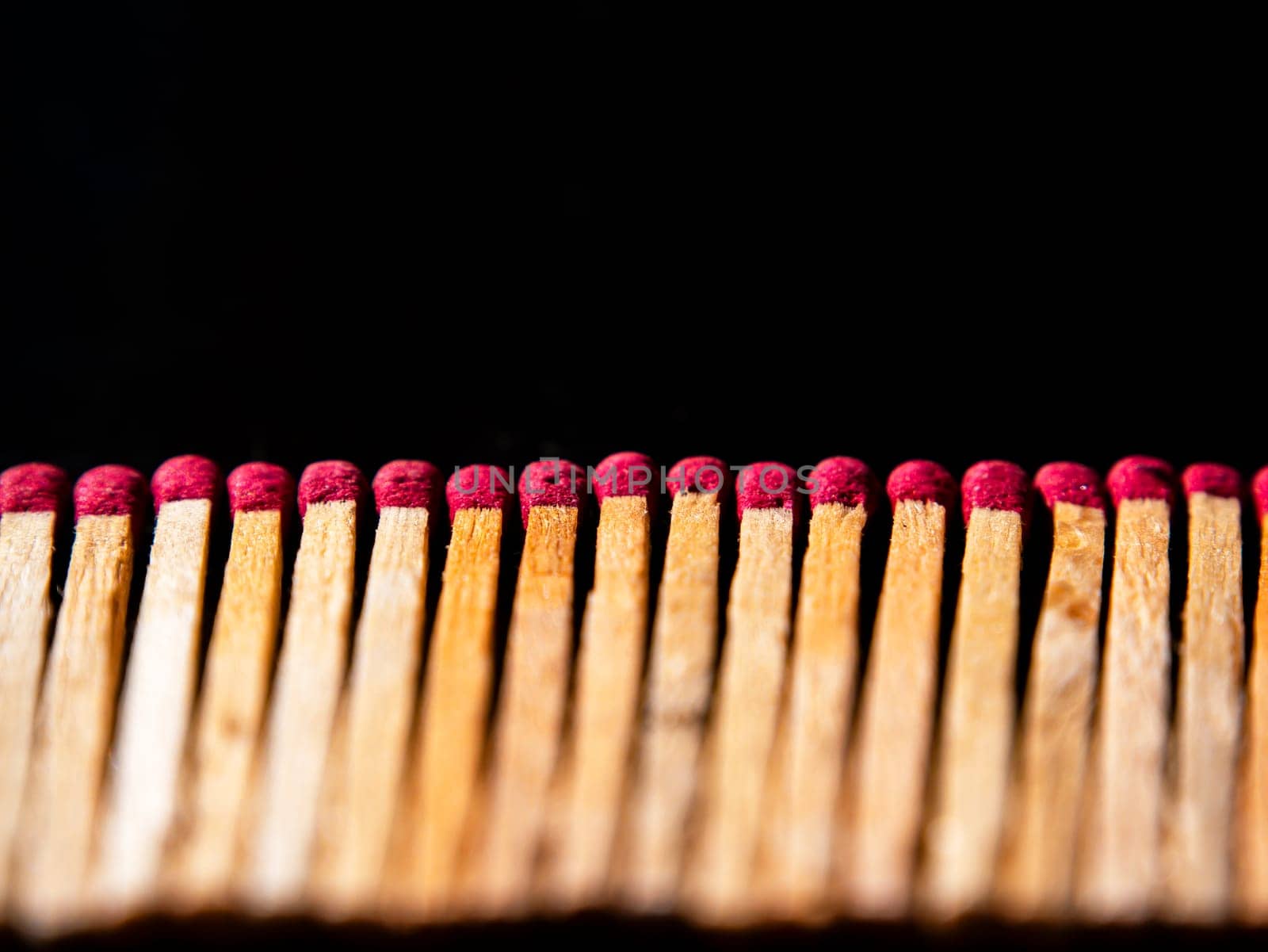 Wooden matches with red sulfur heads on a black background. Fire ignition matches. Matchbox. Red sulfur. Black background. Wood material. Background image. Place for your text.
