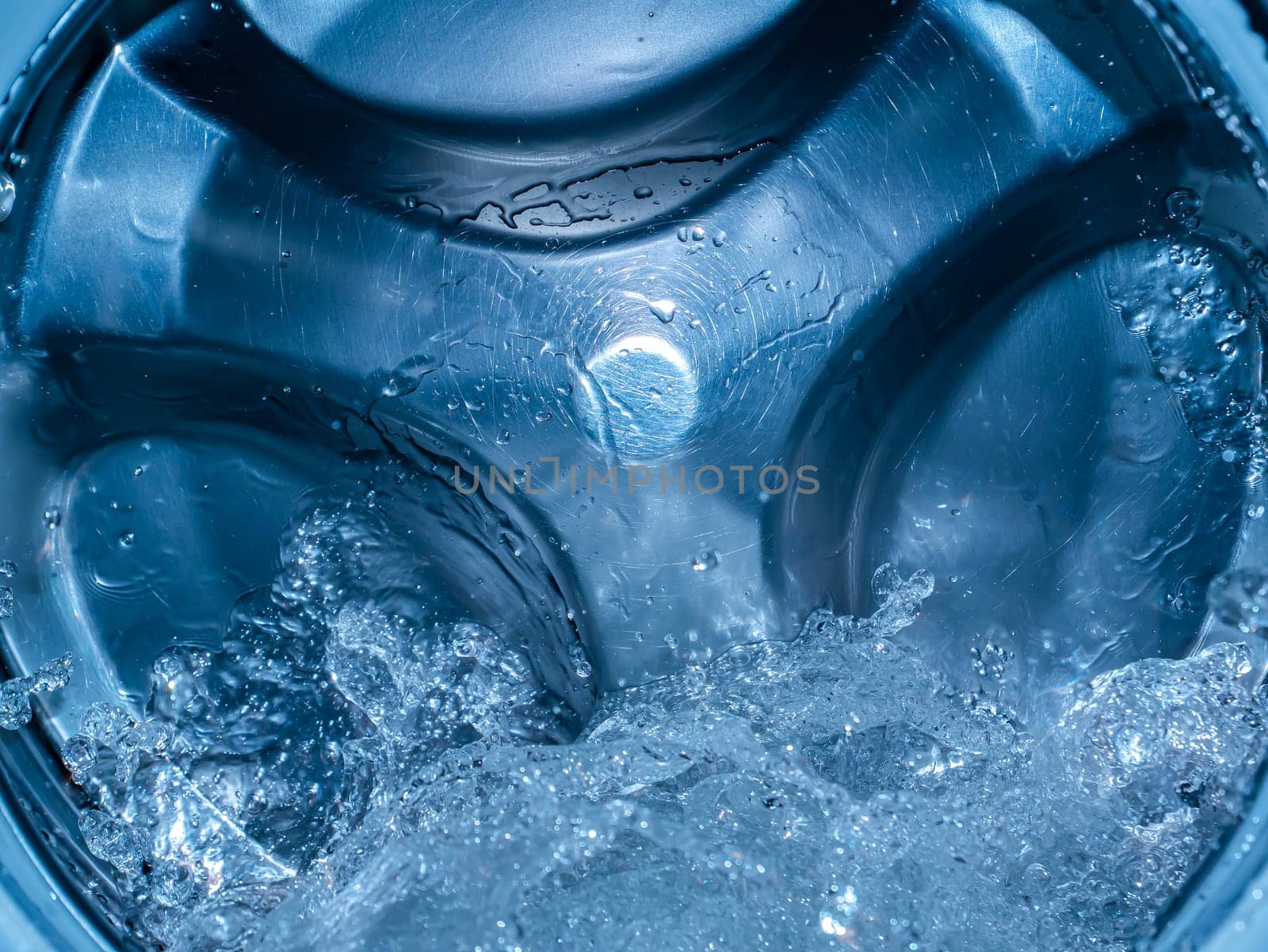 Rotating drum in the washing machine tub with water. Washer. Automatic laundry. Service and repair of equipment. Splashing water. Repair shop. Stainless steel tank. Centrafuga.