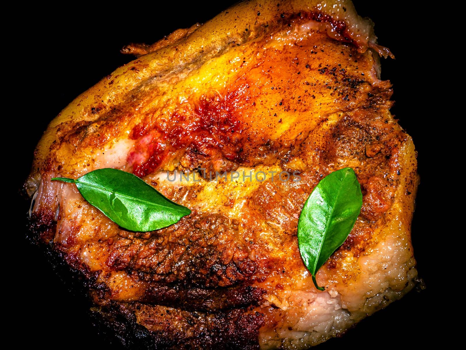 A piece of baked pork with green laurel leaves. Meat dish. Baked ruddy pork skin. Fried lard. Lard cooked on fire. Seasoning with bay leaves. Cooking food. Home kitchen. Kitchen menu.