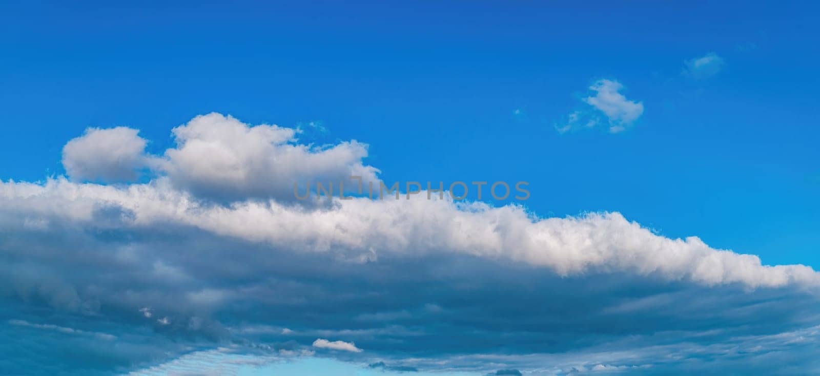 Panoramic photo of the sun against a blue sky with white clouds. Sun glare. Blue sky. White clouds. Space. Atmosphere. Clear day. Natural background. Background image.