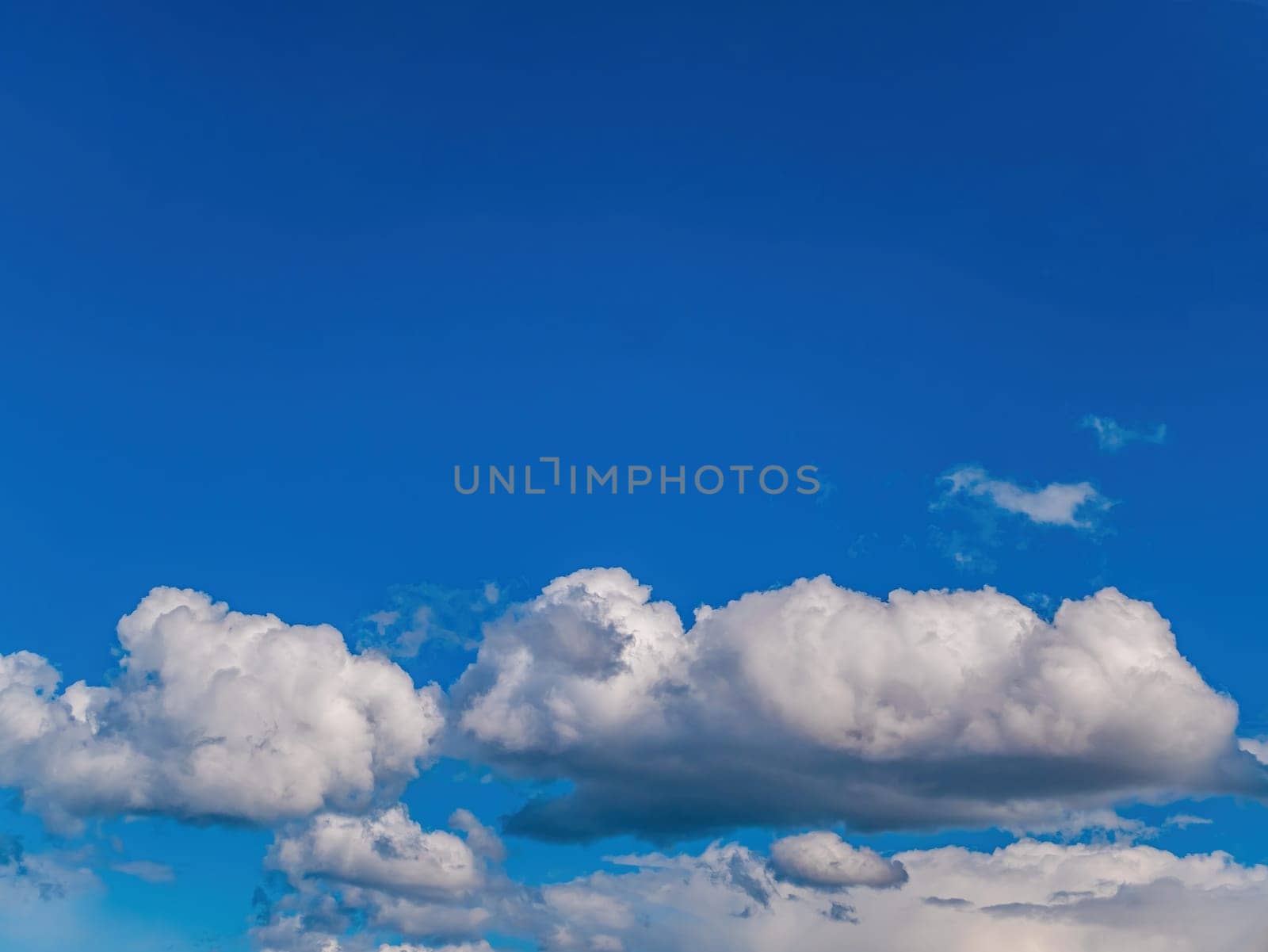 White cloud against blue sky in sunlight. White cumulus clouds. Blue sky. Sunlight. Cloudy horizon. Natural background. Atmosphere and stratosphere. Weather forecast. Space. Air flight.