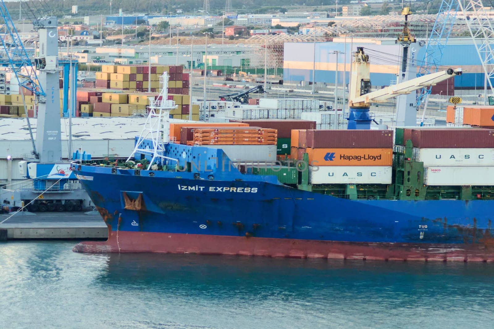 Civitavecchia, Italy - February 17, 2025: Cargo ship IZMIT EXPRESS docked in the port of Civitavecchia, Italy, with containers stacked on the deck. Busy port scene with cranes and stacked containers.