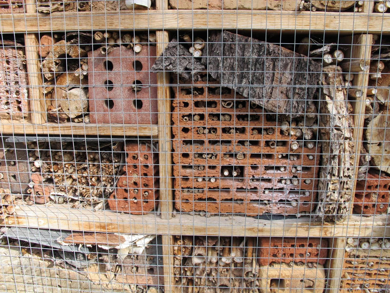 Insect hotel with brick, bamboo sticks, bark and log