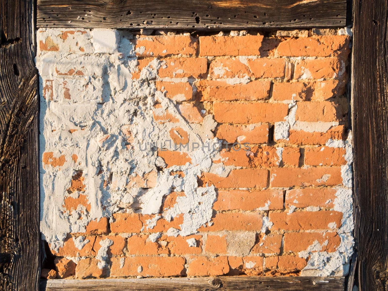 Detailed view of a half-timbered wall with exposed bricks and cement stains in the light of the evening sun.