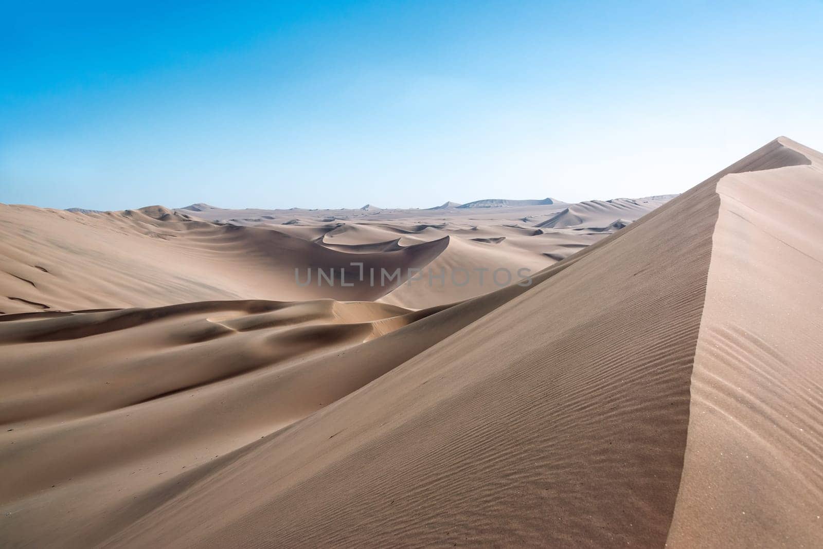 Sand dune landscape seen from the top of a dune at Huacachina, Peru