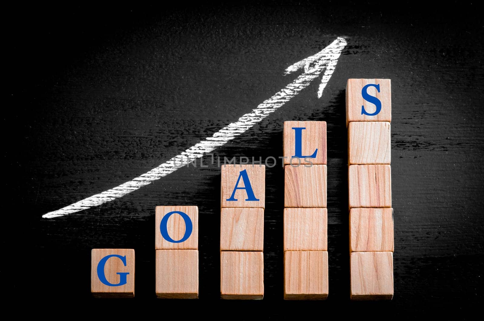 Ascending arrow above bar graph of Wooden small cubes isolated on black background. Chalk drawing on blackboard. Business Concept image.