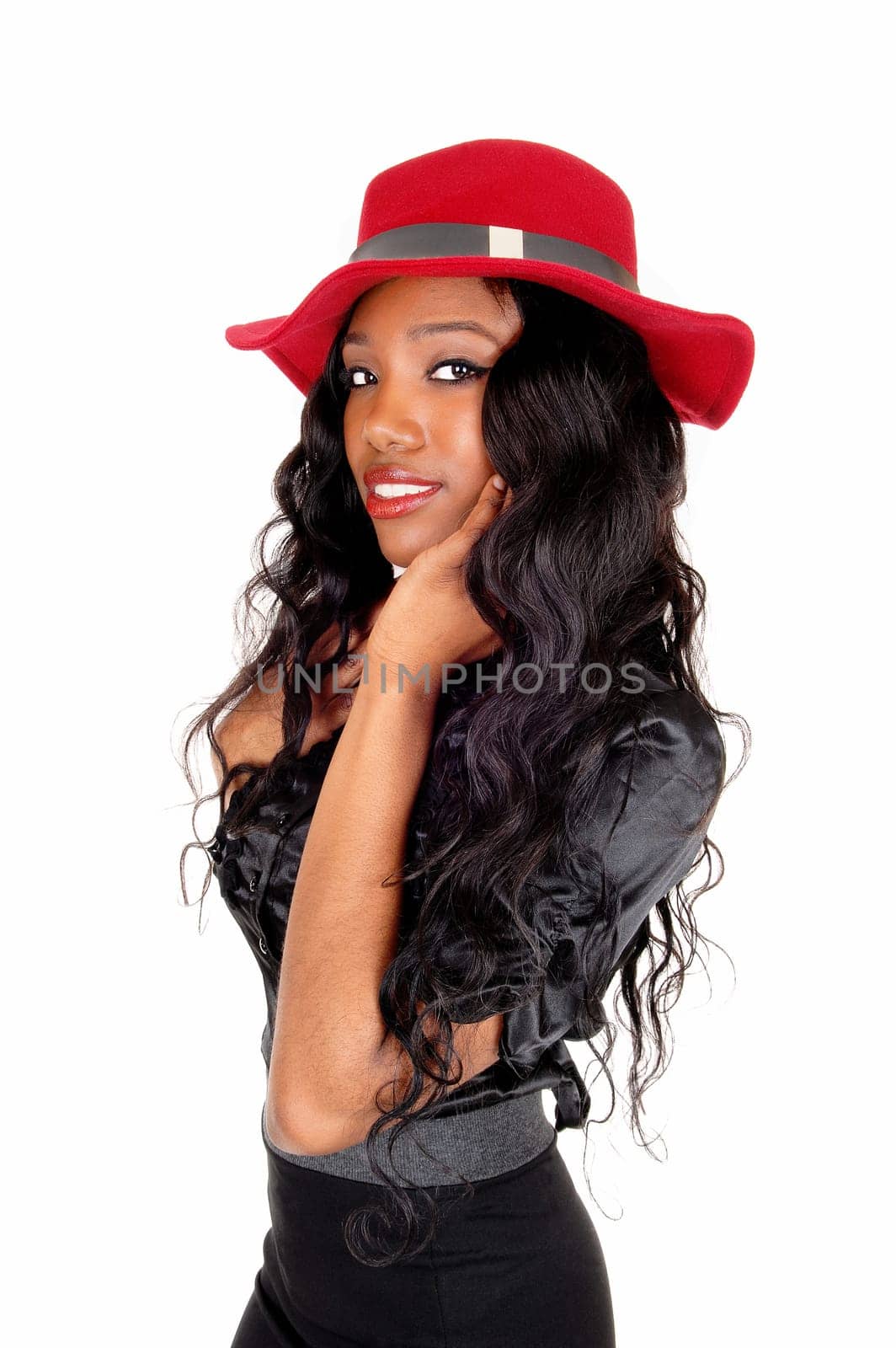 A beautiful African American woman in a black skirt and blouse with a.red hat standing in profile, isolated for white background..