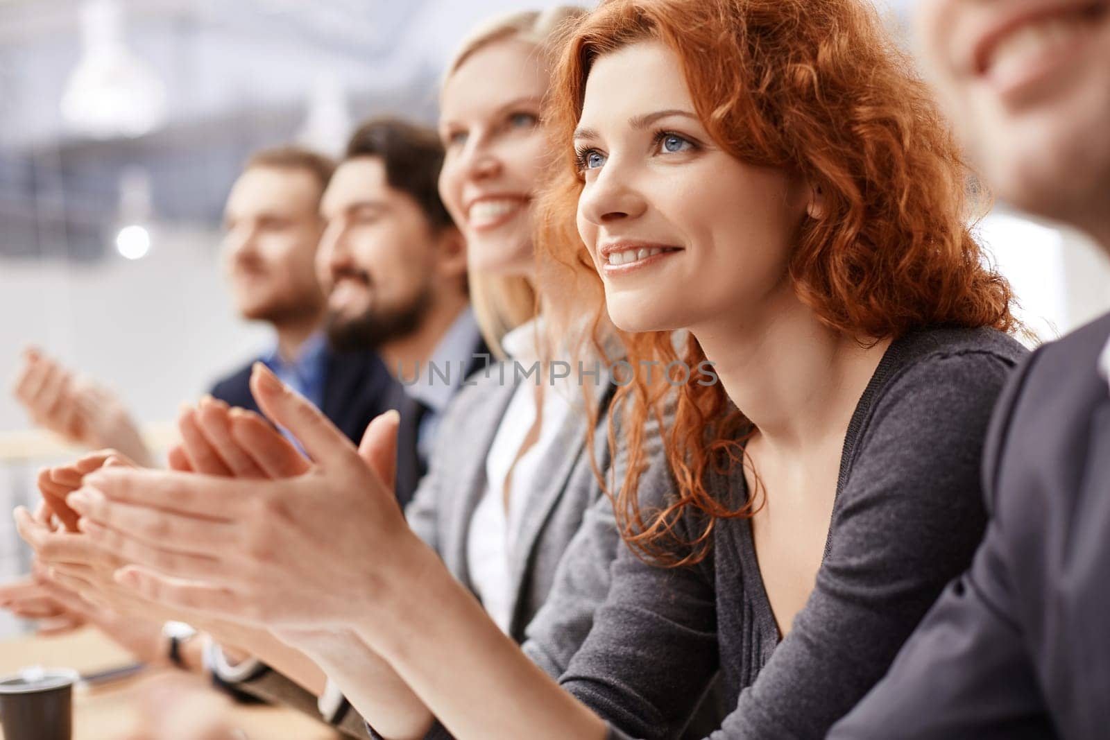 Smiling female applauding at conference between her colleagues