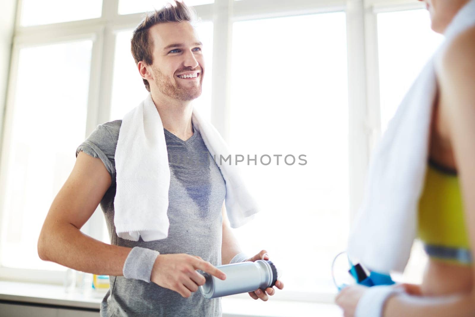 Young man with water container talking to girl in gym
