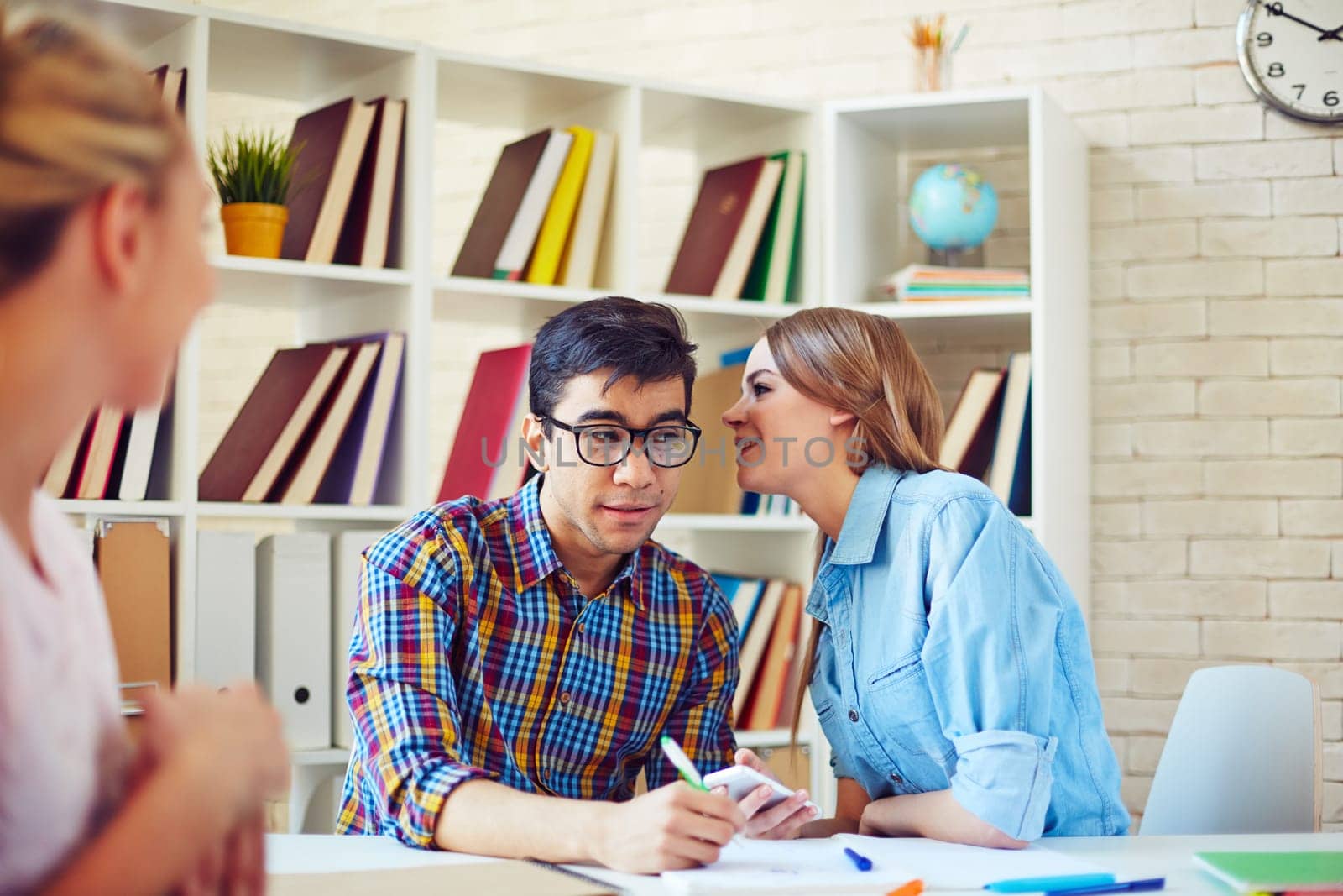 Teenage girl whispering secret to her groupmate