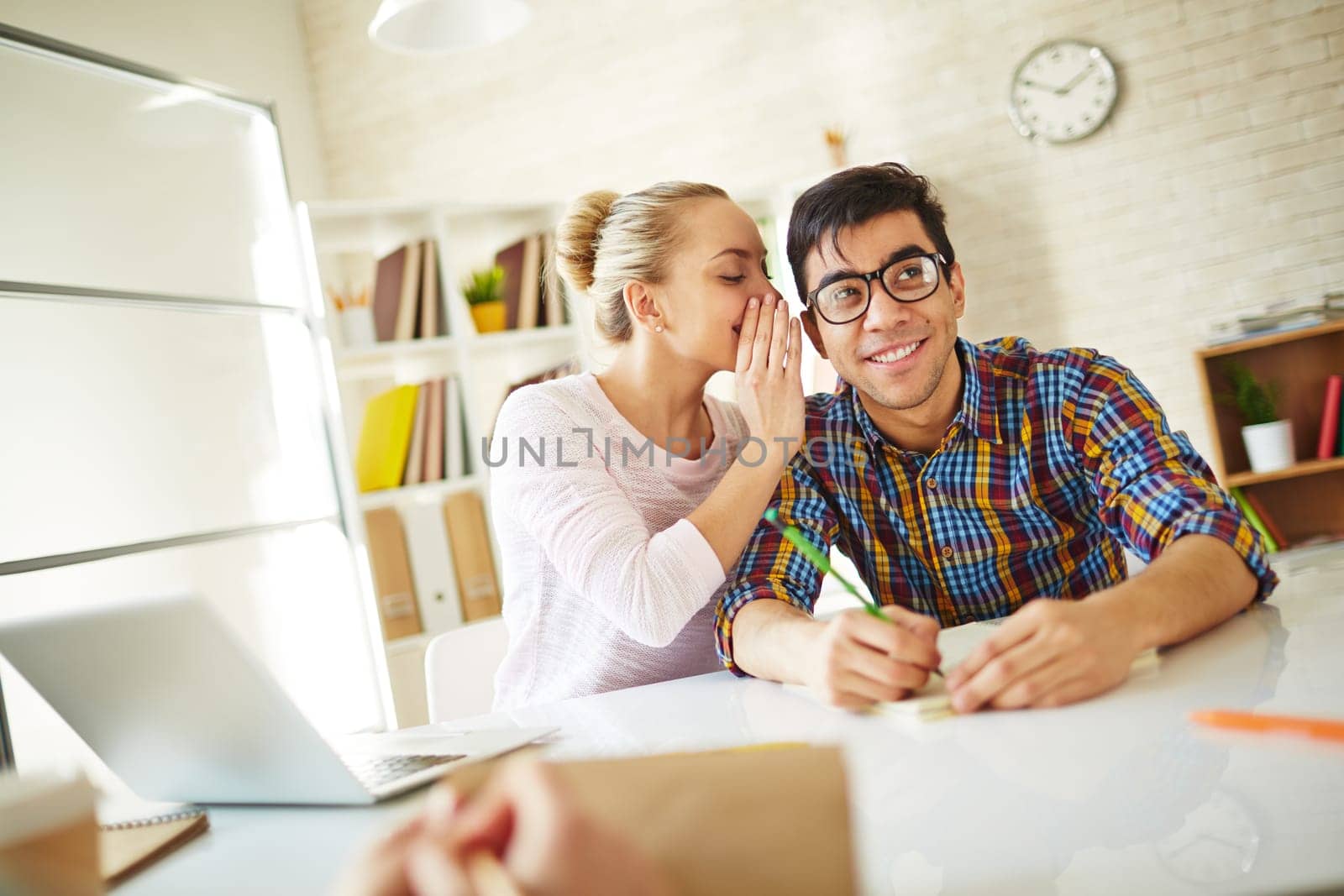 Teenage girl whispering fun to attractive groupmate