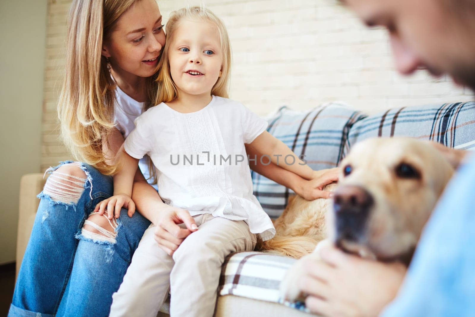 Cute little girl looking at dog with her mother near by