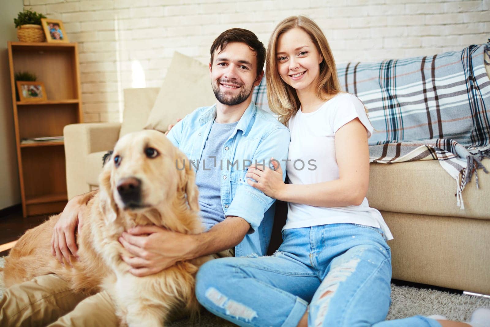 Happy young couple and their pet enjoying home rest on weekend
