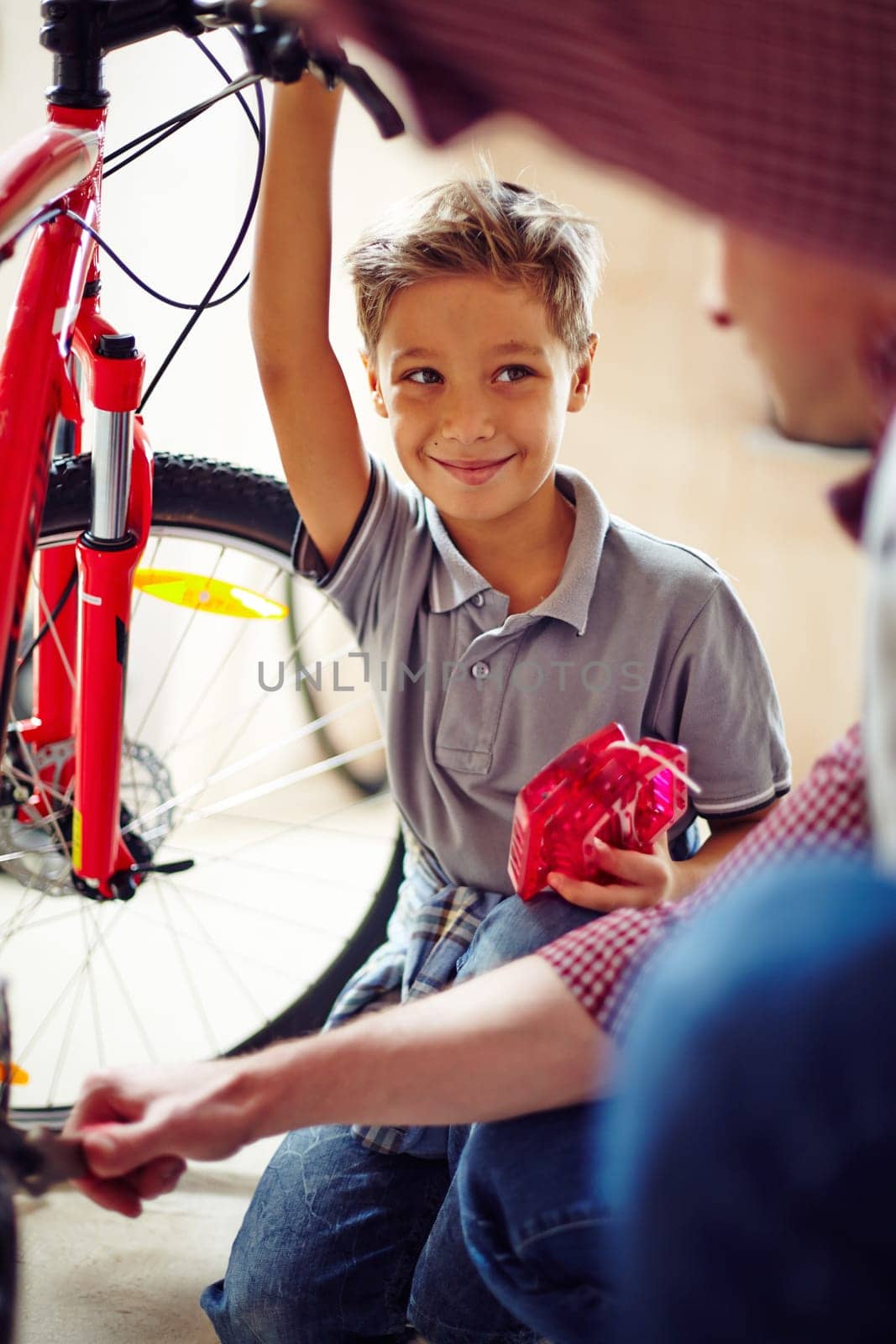 Happy little boy looking at his father in garage