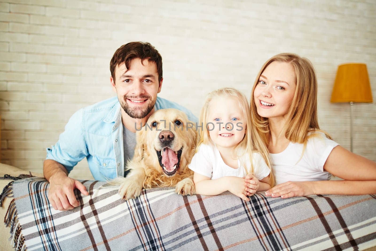 Happy young couple with their daughter and dog looking at camera