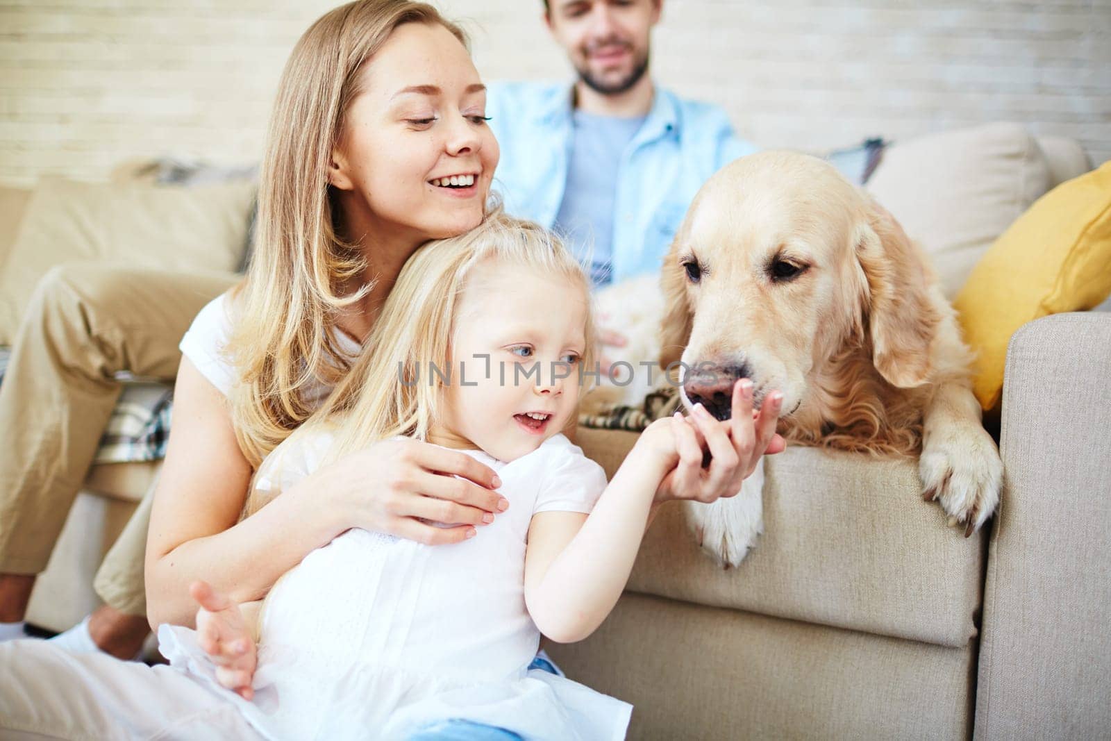 Happy female and her daughter looking at dog with young man on background