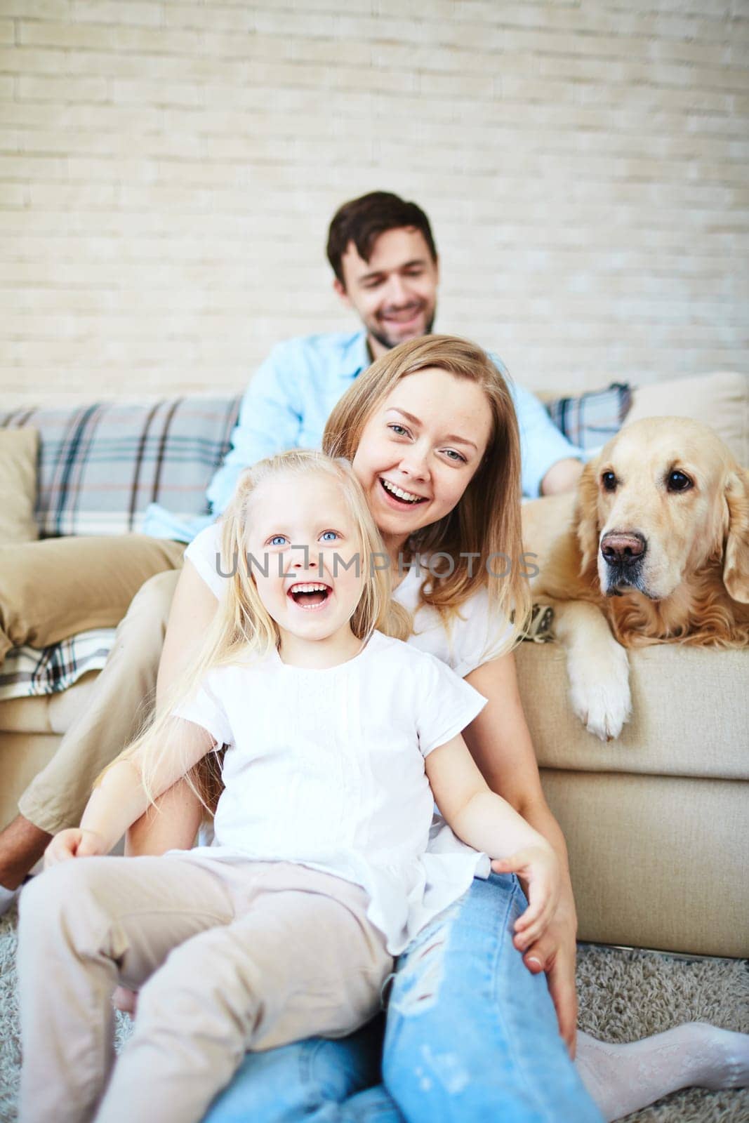 Happy female and little girl laughing with dog and young man on background