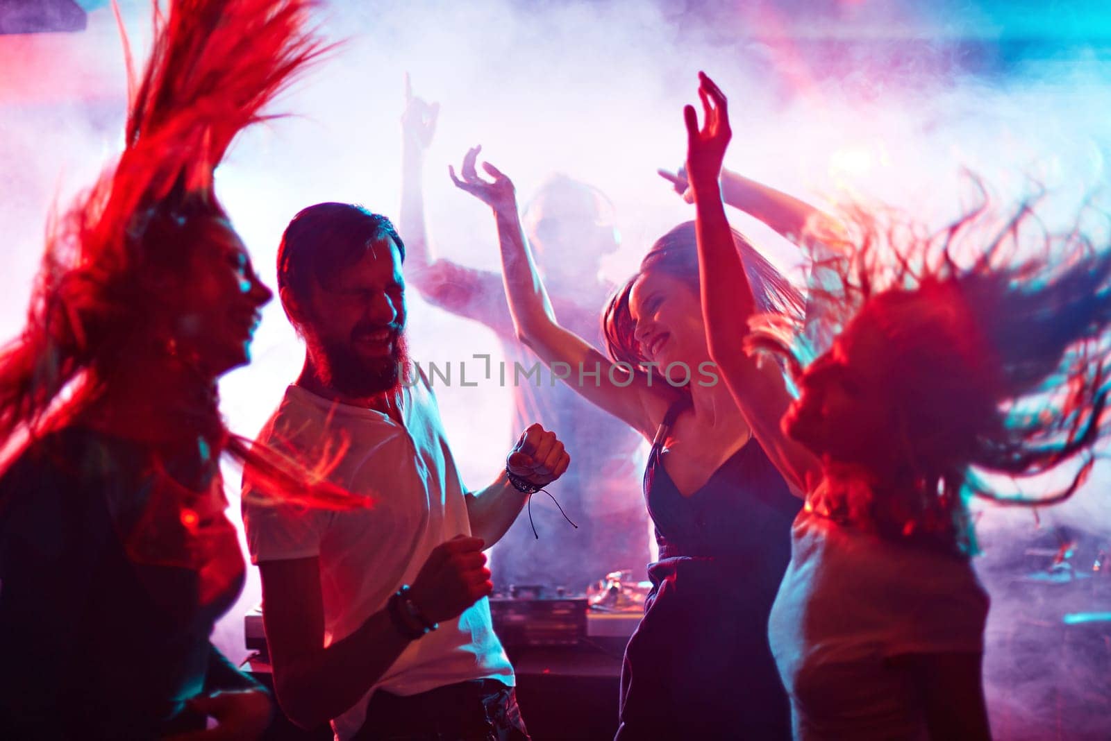 Group of energetic friends dancing in night club