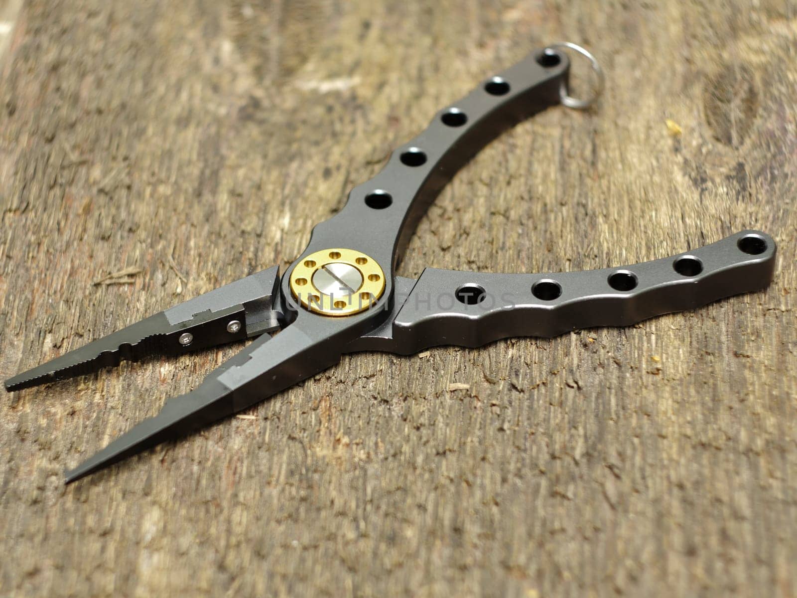 modern fishing pliers on wooden background close-up