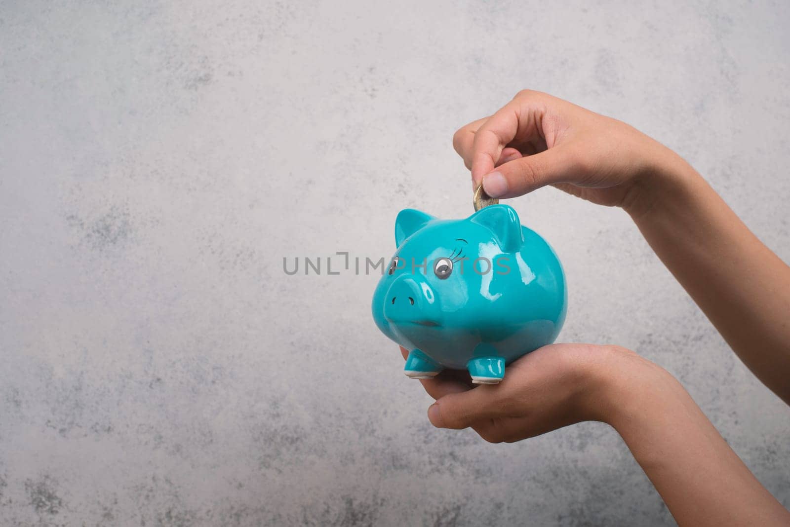 Putting money into a blue piggy bank, empty copy space for text