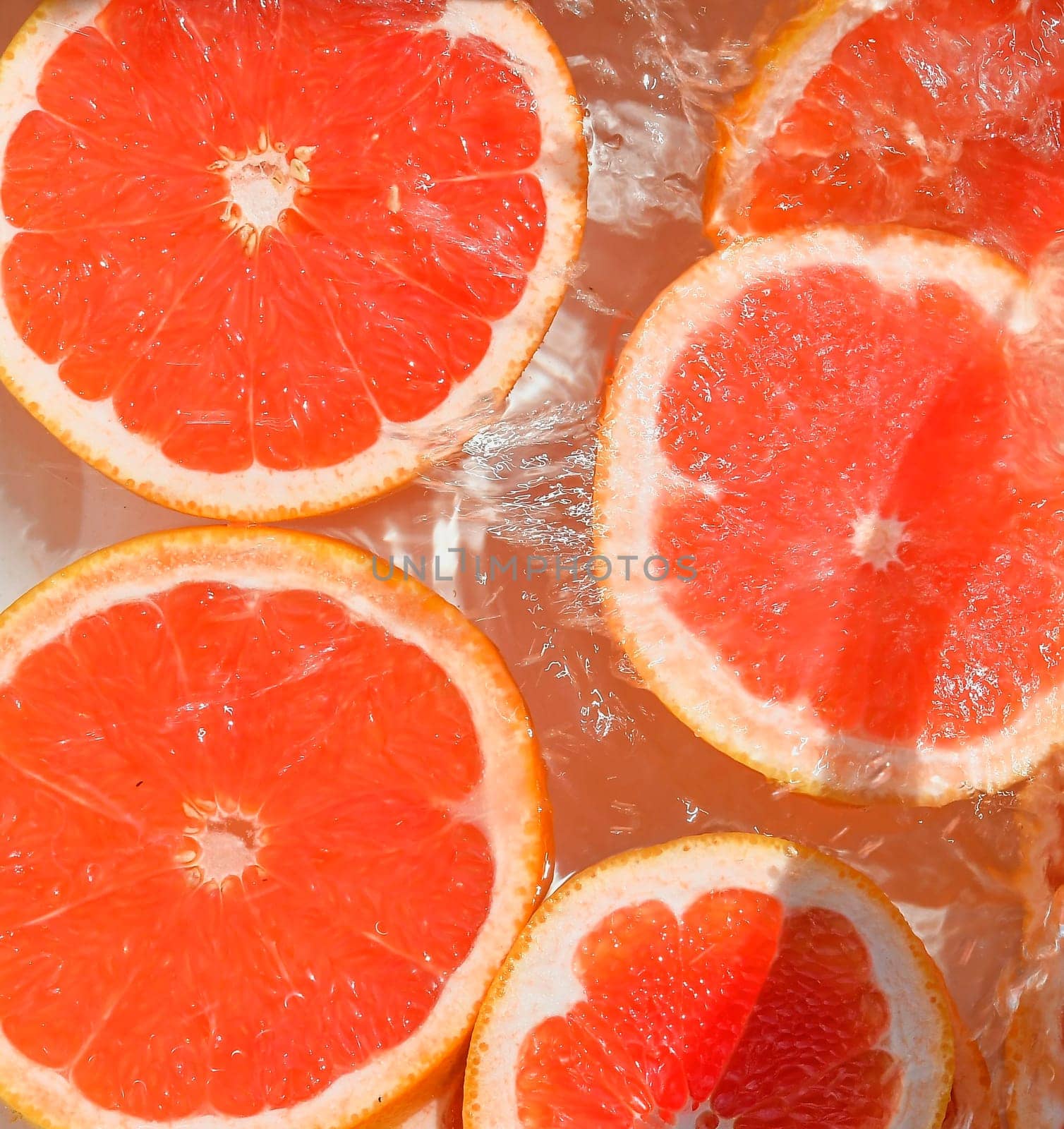 Close up view of the red grapefruit slices in lemonade background. Texture of cooling sweet summer's drink with macro bubbles on the glass wall. Flat design.