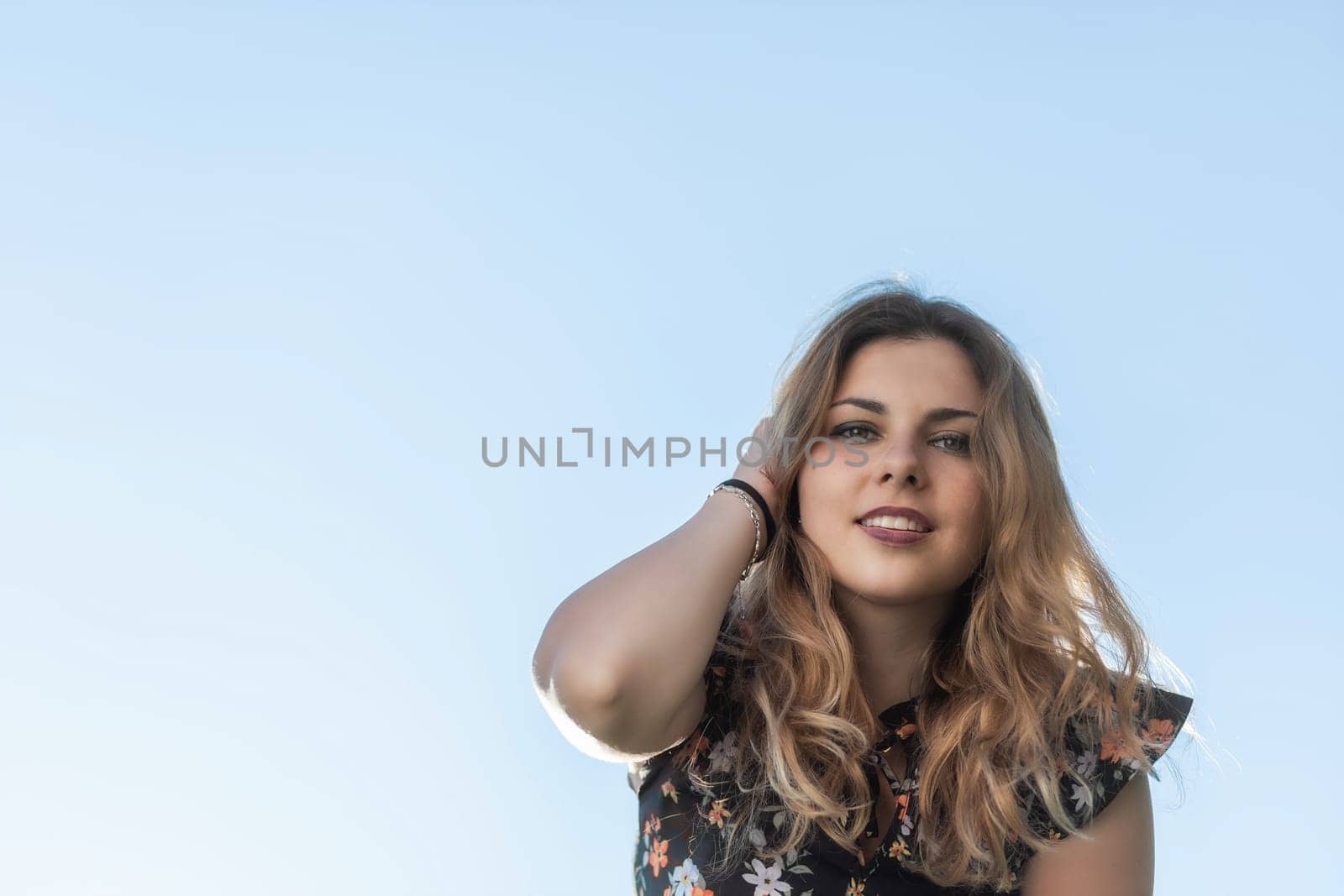 Portrait of smiling attractive young woman. Blue sky in the background. Horizontally.