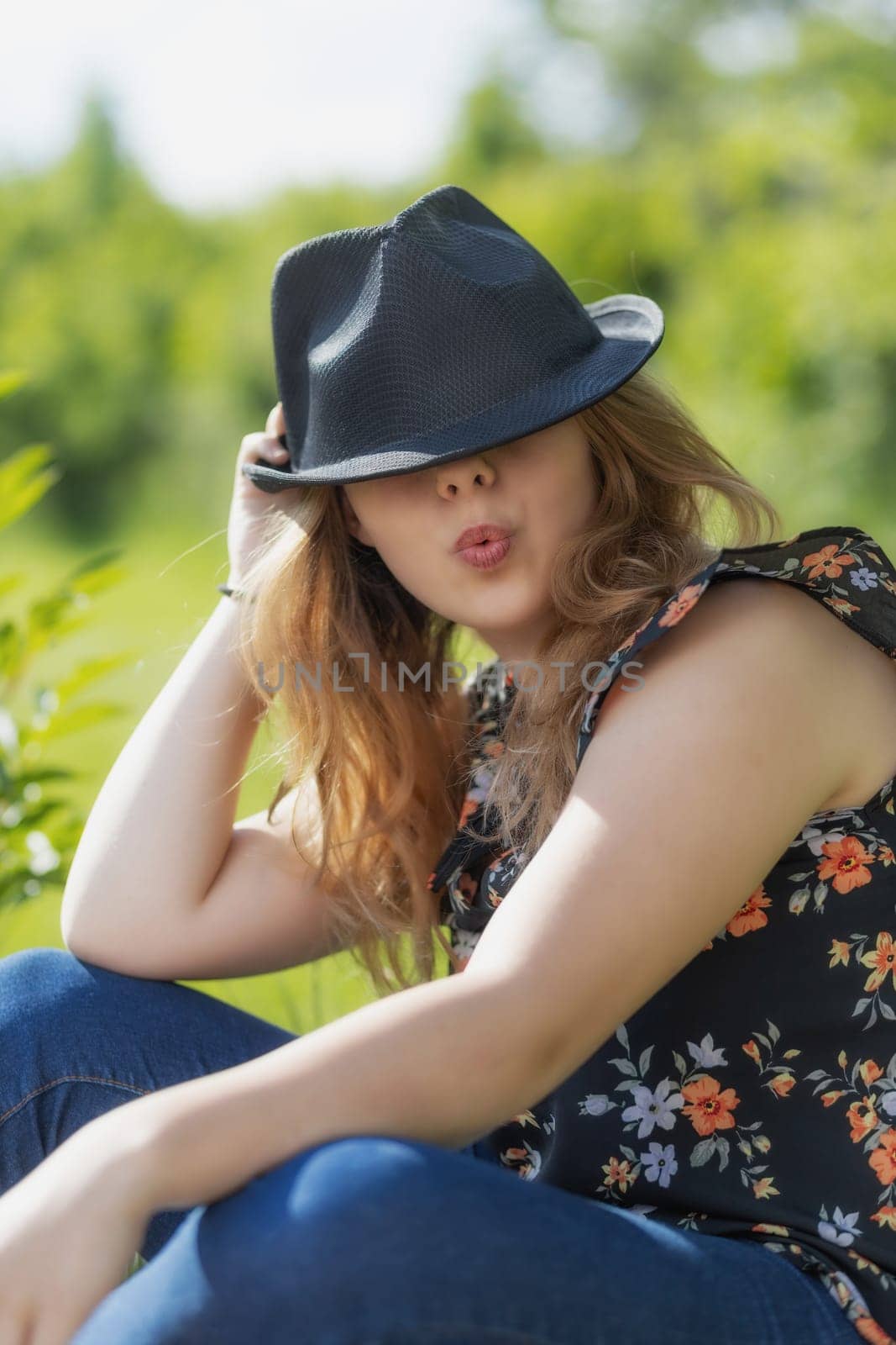 Portrait of bautiful young woman with pursed lips is posing in black hat Vertically.