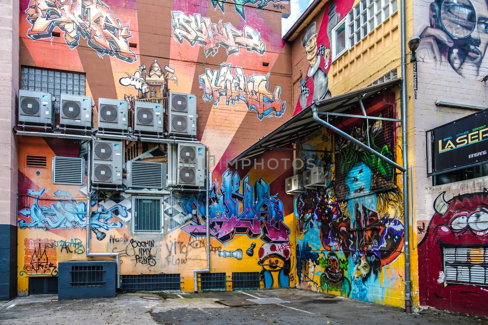 WETZLAR, GERMANY - 23.05.2021: Air conditioner mounted on a house facade with surround colorful graffiti.