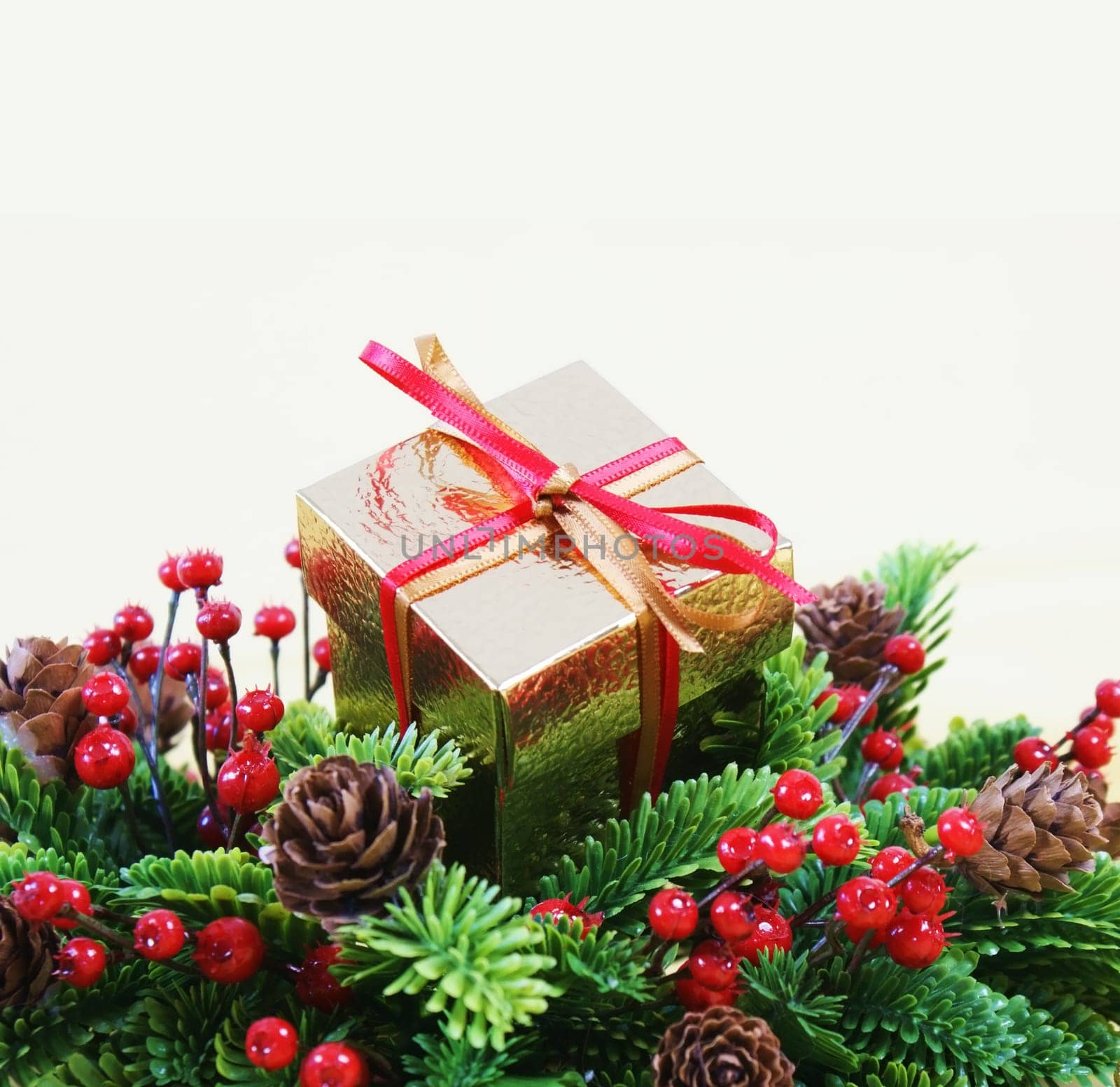 Christmas gift in a wreath with berries and pine cones