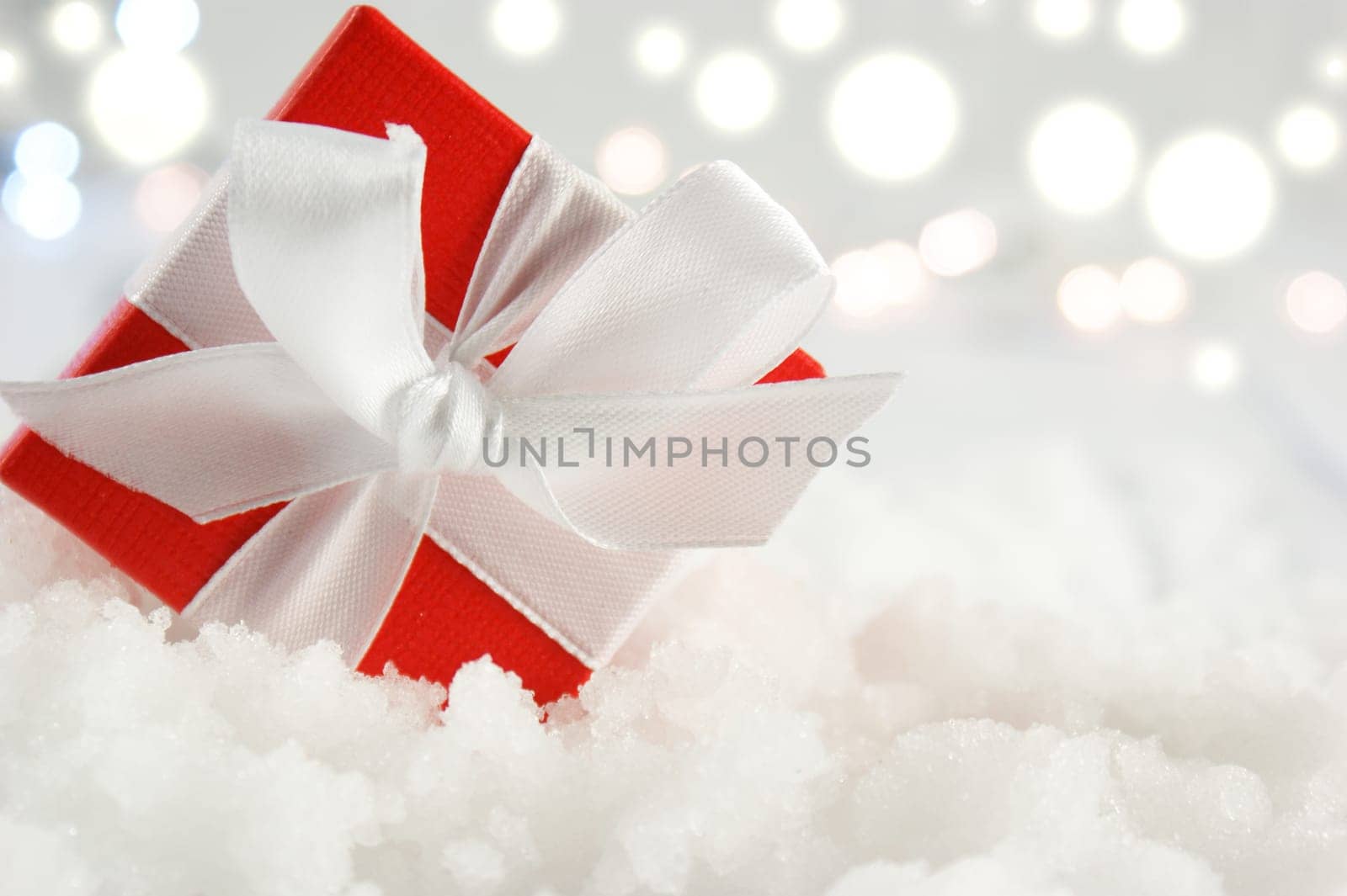 Christmas gift nestled in snow on a bokeh lights background
