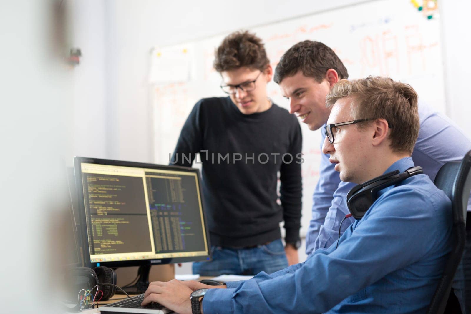 Startup business and entrepreneurship. Young software developers team brainstorming and programming on desktop computer in startup company share office space.