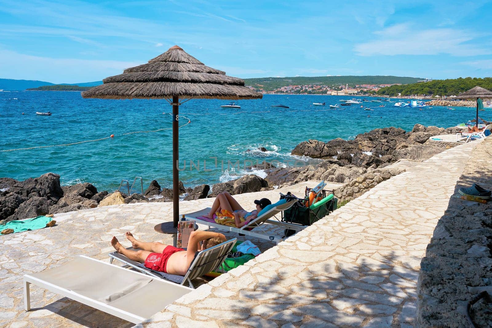 Holidaymakers sunbathing at a typical bathing spot on the rocky coast near Krk in Croatia