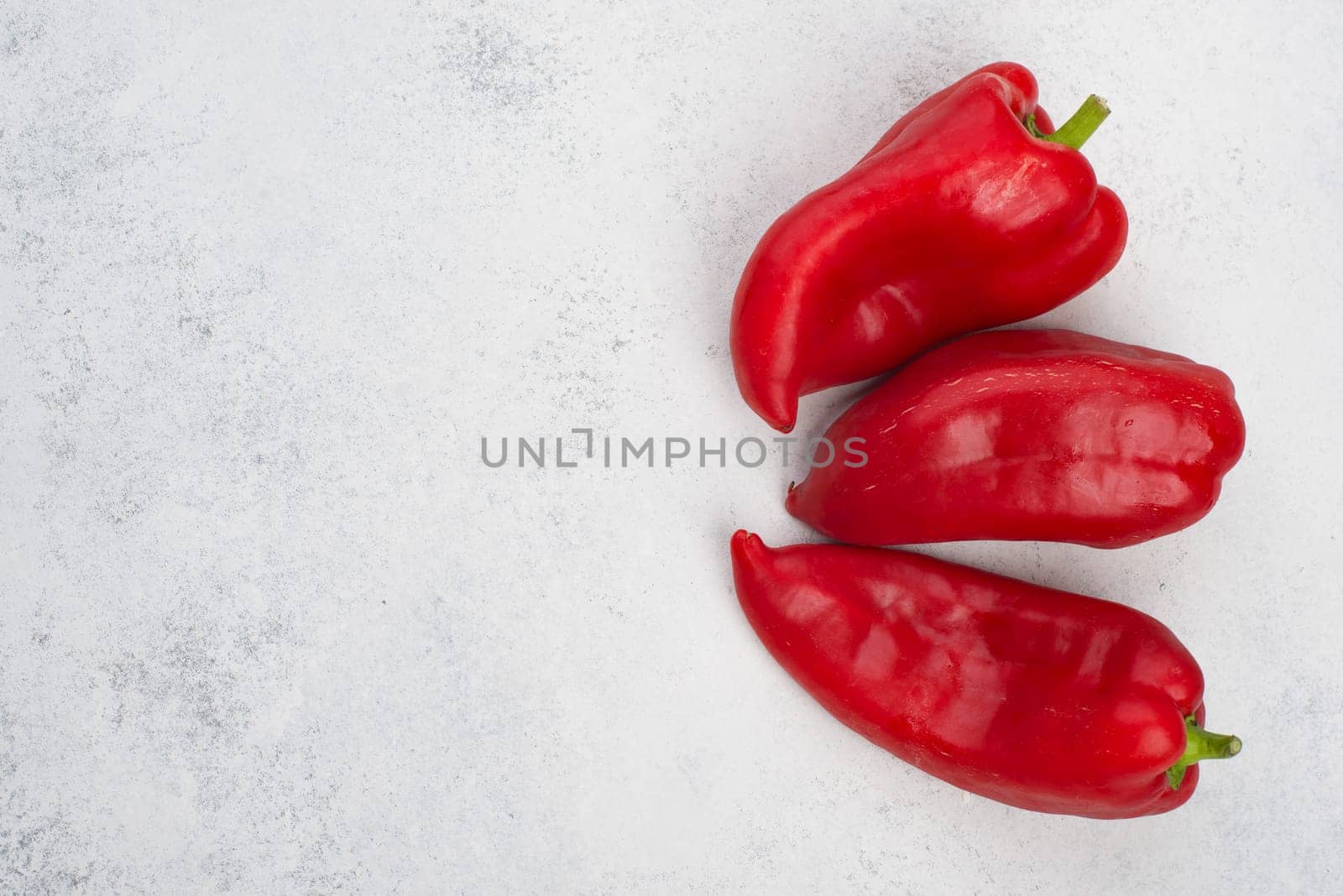 Fresh red paprika isolated on a white textured background, empty copy space for text