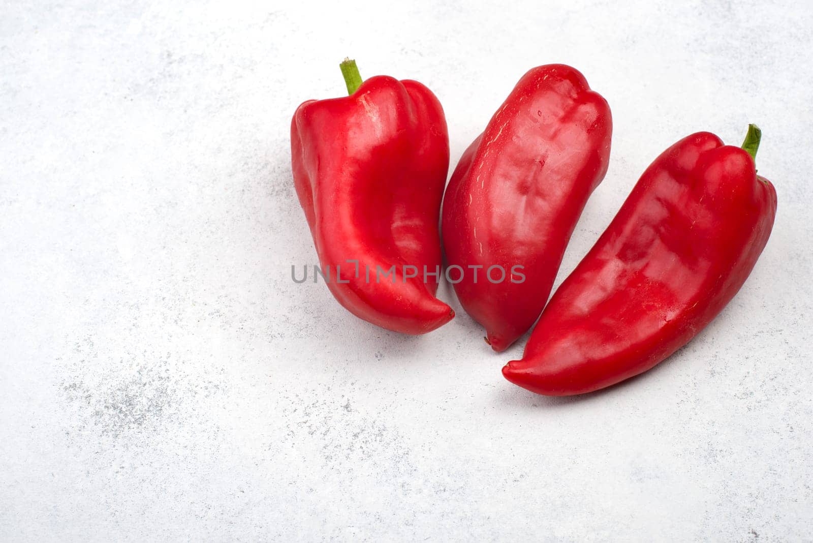 Fresh red paprika isolated on a white textured background, empty copy space for text