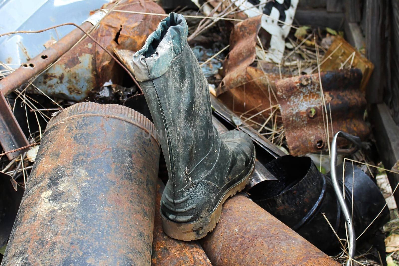 Closeup of an old boot ontop of a rusty metal garabge pile.
