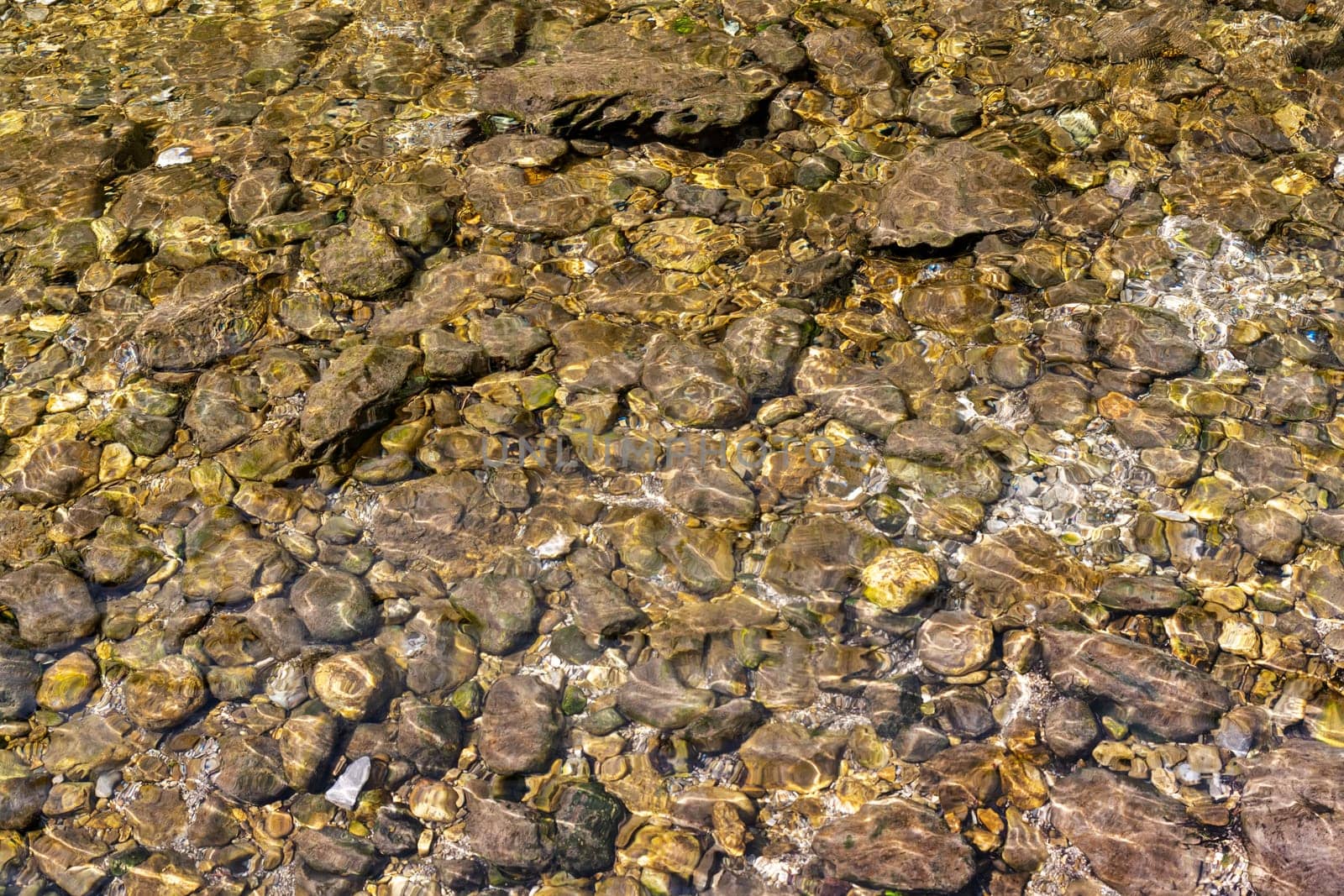 Pebbles under the water surface of a stream as a background