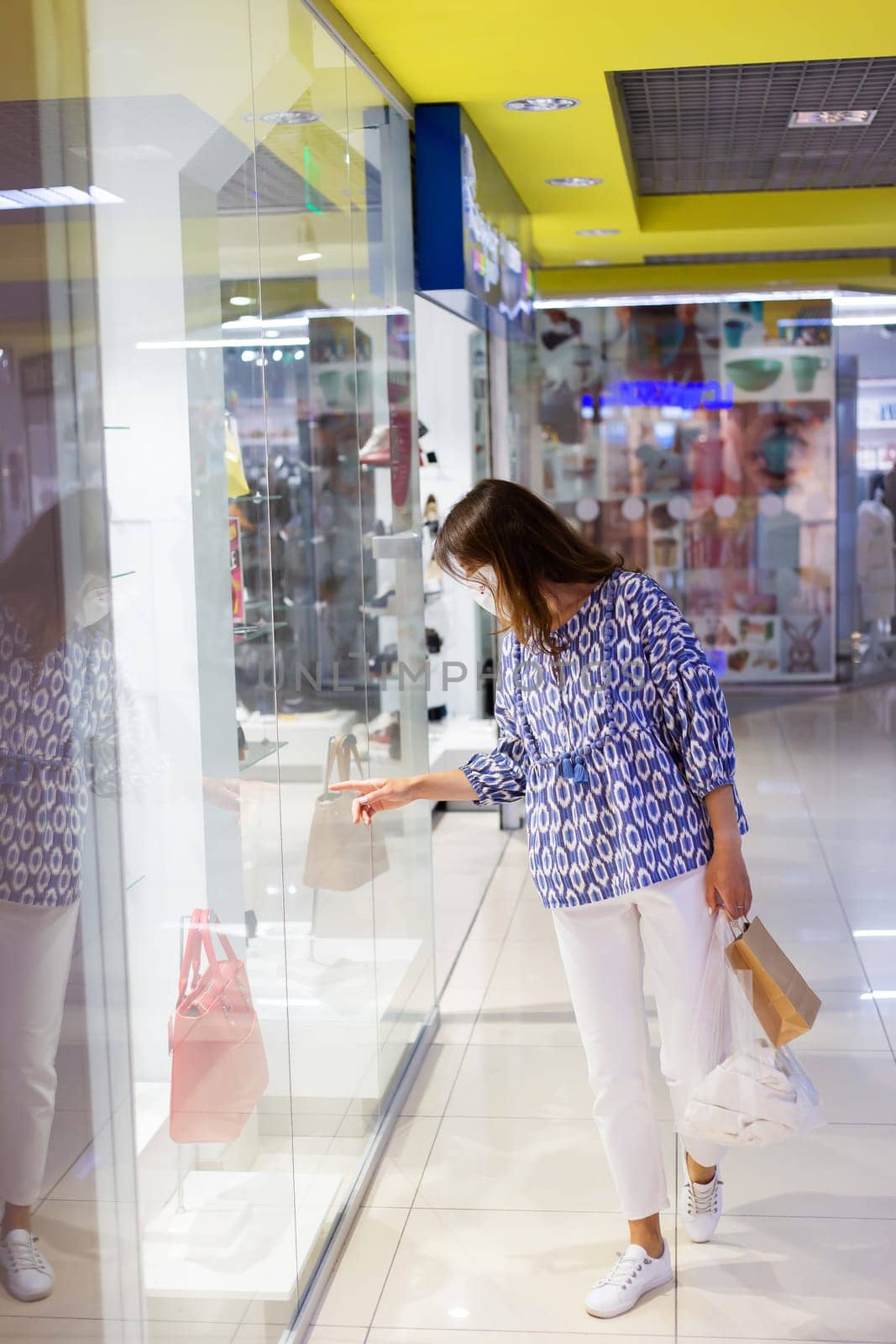 A young girl carrying shopping bags walks through a mall wearing a medical mask during the coronavirus pandemic