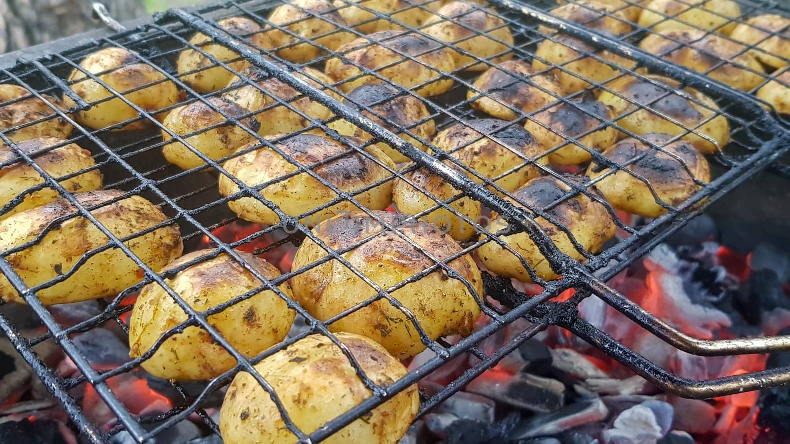 Grilled potatoes with bacon, whole baked on the barbecue grill. Selective focus. Whole small potatoes with bacon bits and grilled. Baked potatoes with grilled bacon