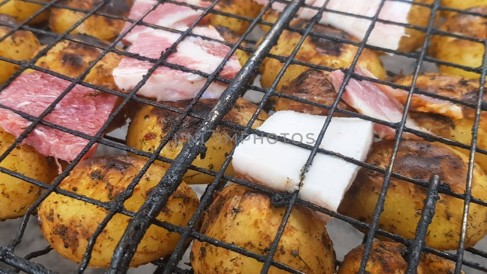 Grilled potatoes with bacon, whole baked on the barbecue grill. Selective focus. Whole small potatoes with bacon bits and grilled. Baked potatoes with grilled bacon