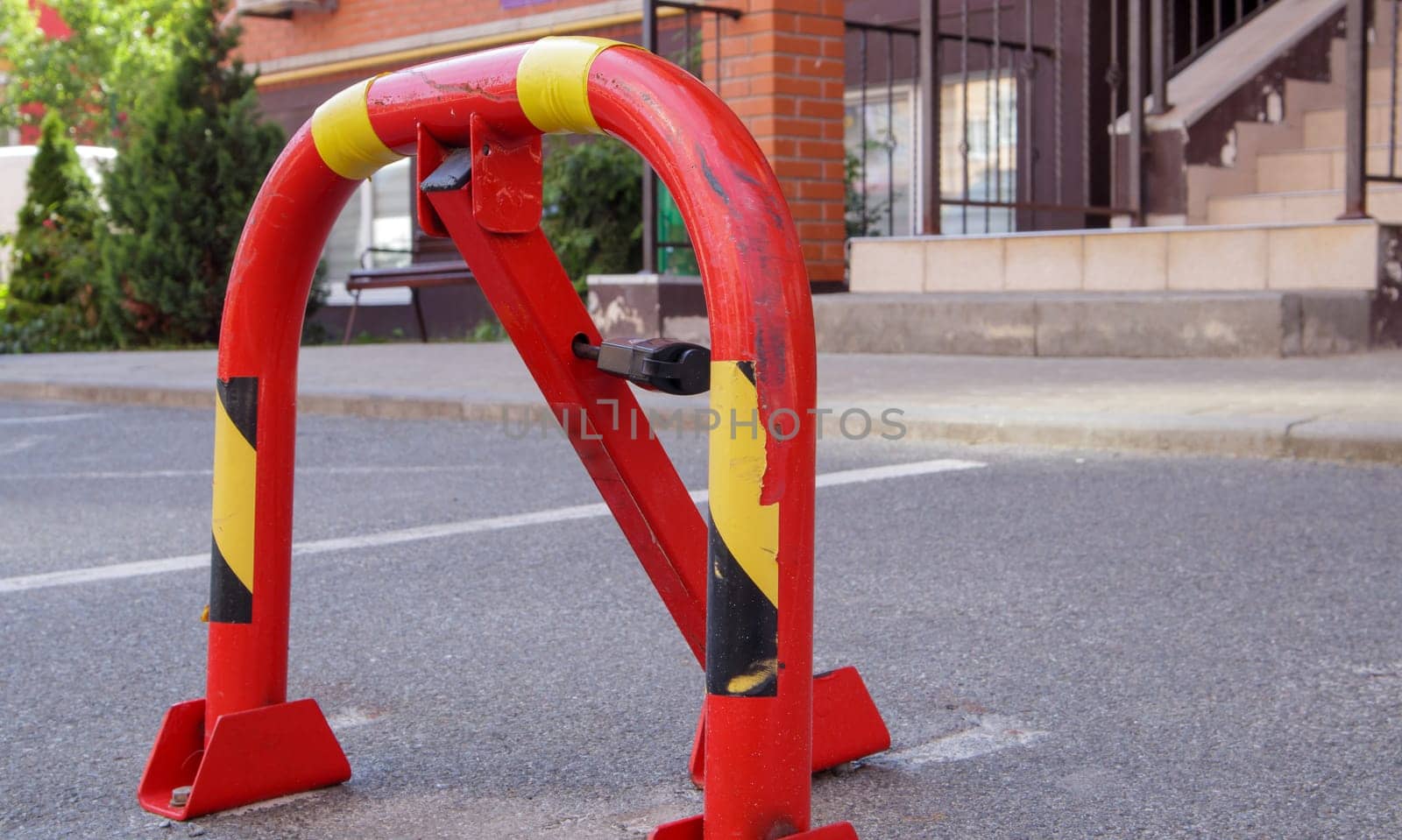Manual red metal parking barrier with lock. Parking lock device. Parking barrier installed. A foldable barrier prevents the vehicle from stopping at this point. Reserved seat