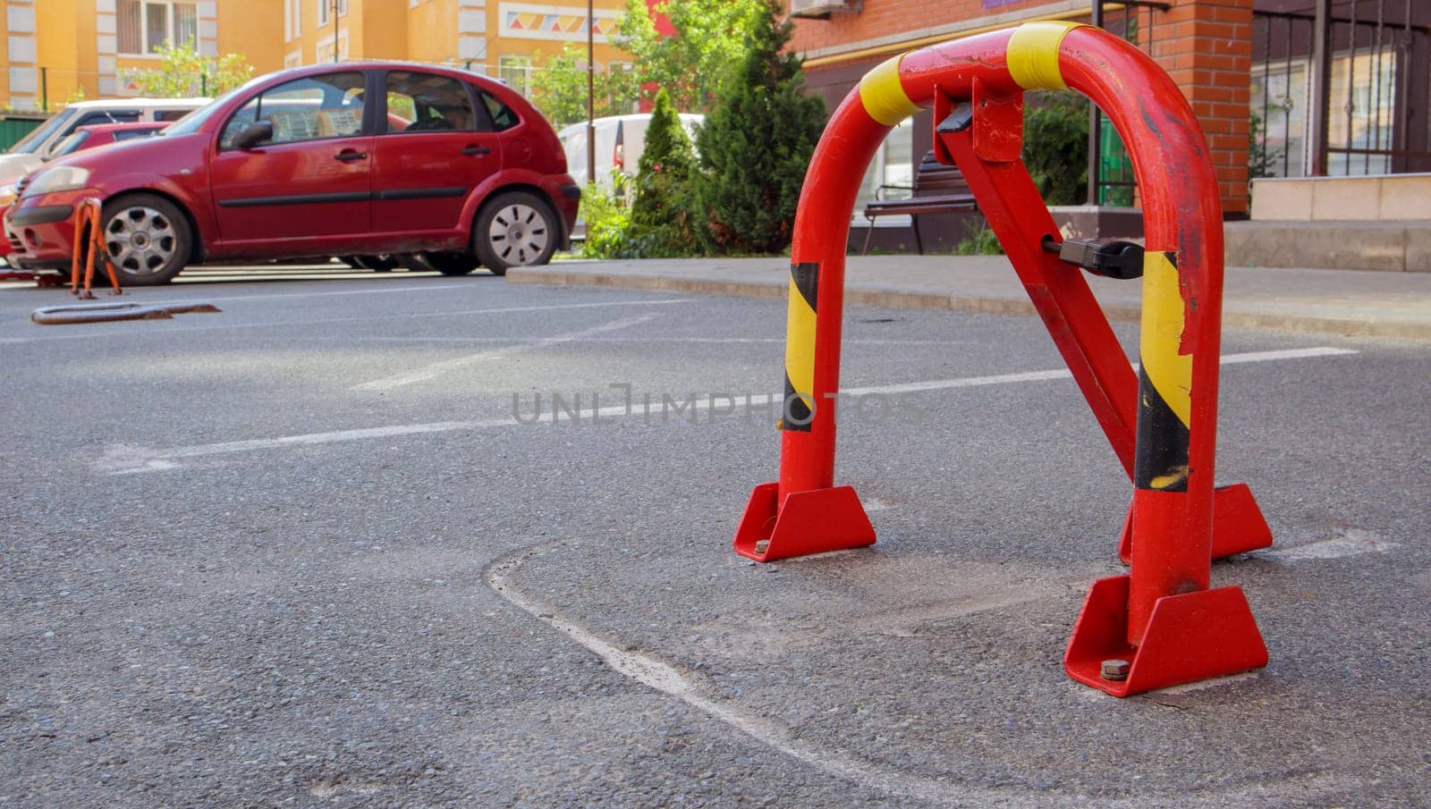 Manual red metal parking barrier with lock. Parking lock device. Parking barrier installed. A foldable barrier prevents the vehicle from stopping at this point. Reserved seat