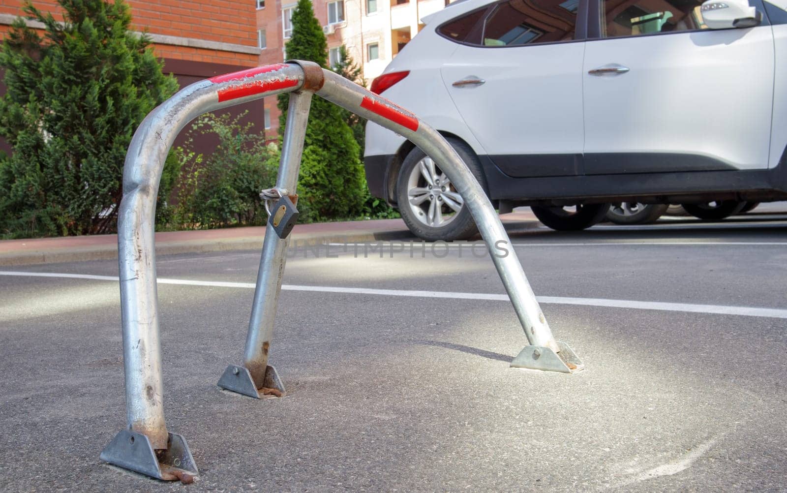 Manual gray galvanized metal parking barrier with lock. Parking lock device. Parking barrier installed. A foldable barrier prevents the vehicle from stopping at this point. Reserved seat