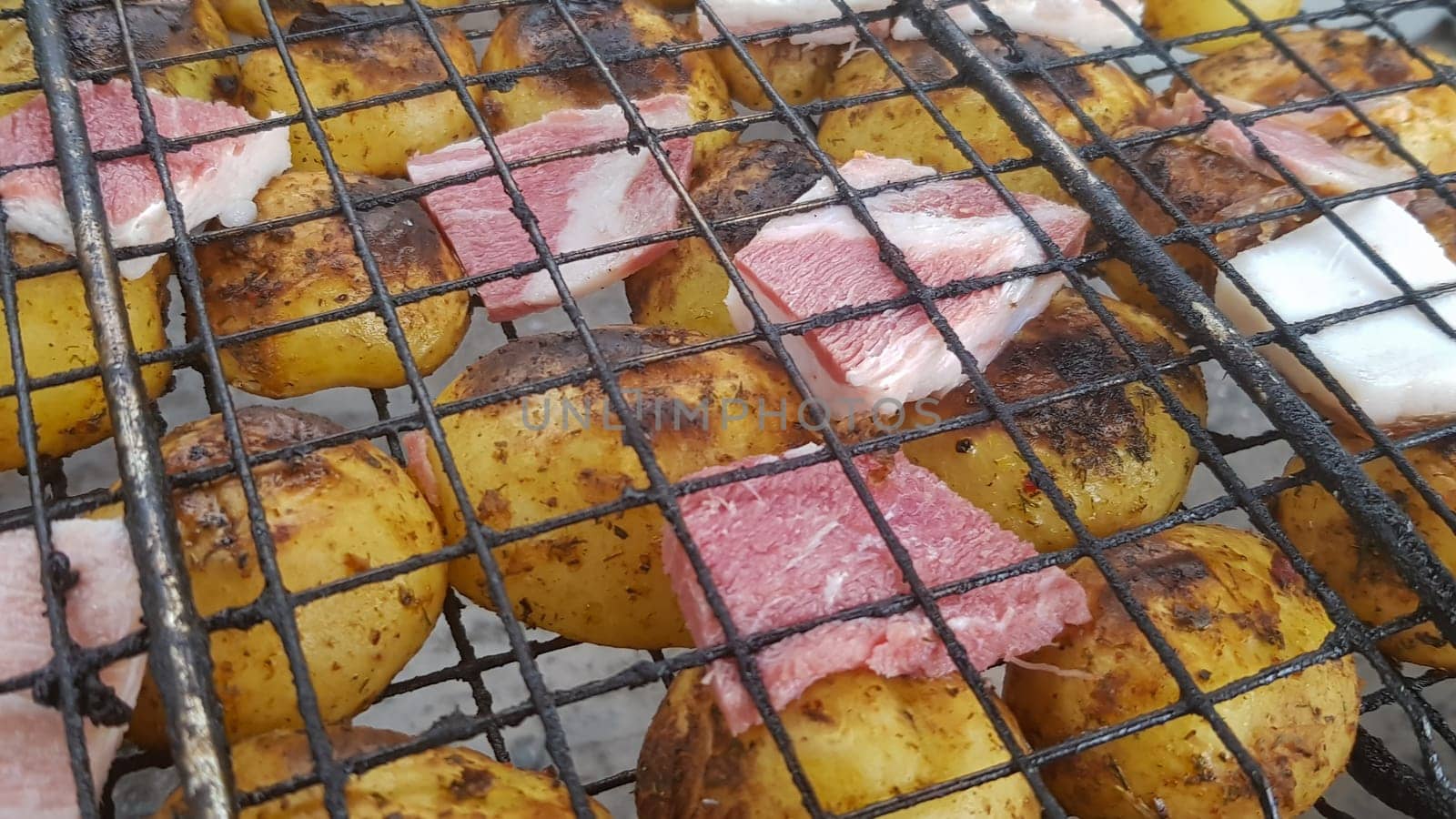 Grilled potatoes with bacon, whole baked on the barbecue grill. Selective focus. Whole small potatoes with bacon bits and grilled. Baked potatoes with grilled bacon