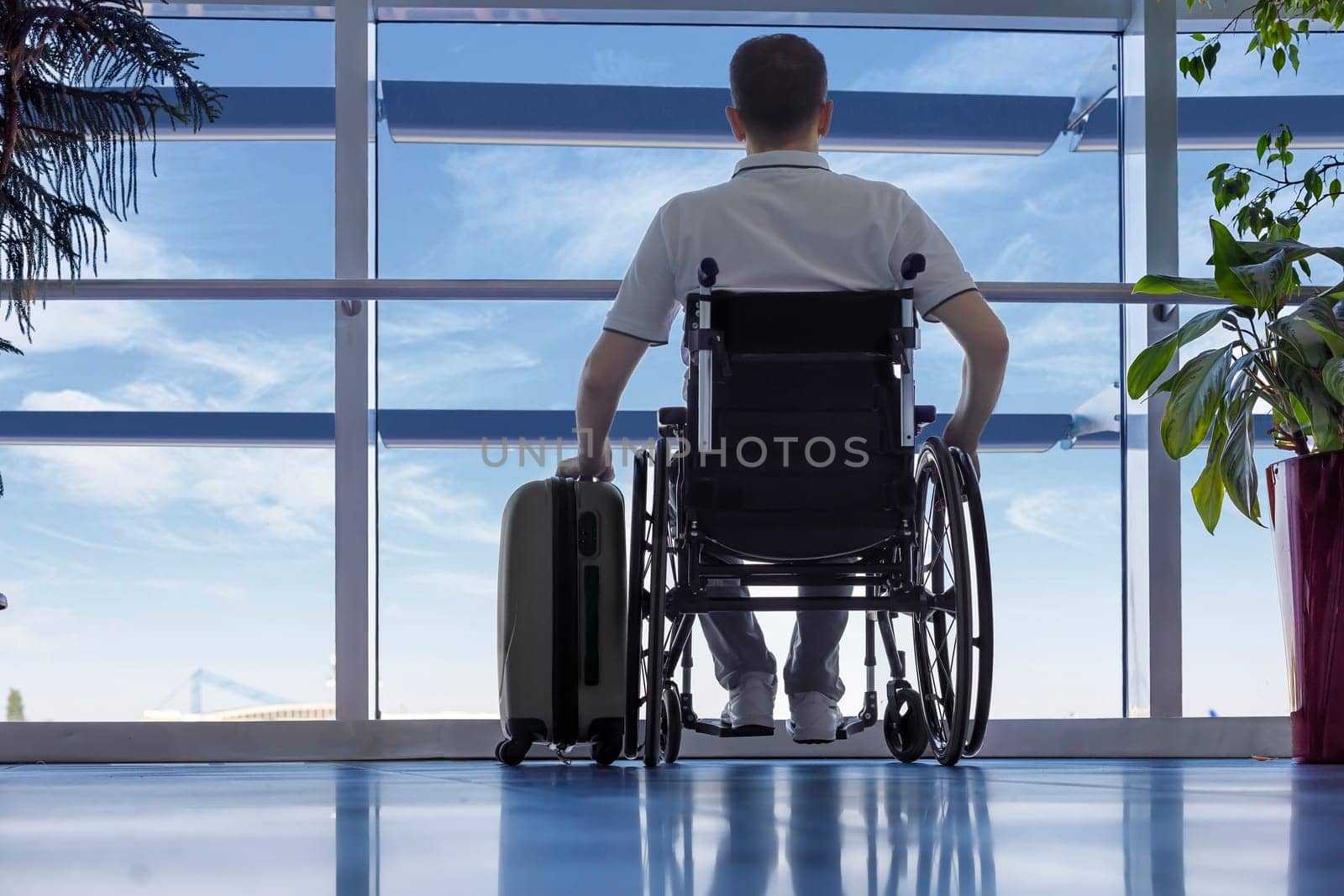 Young man in a wheelchair with luggage at the airport closeup