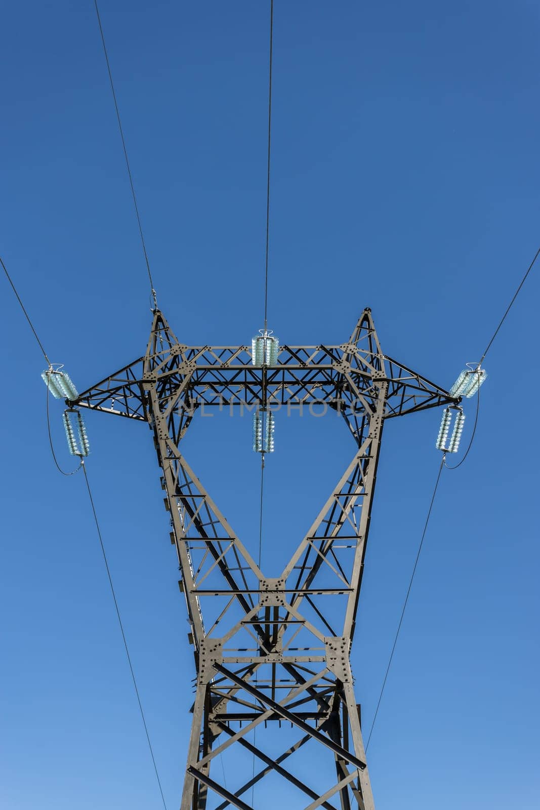 Electricity pylon silhouetted against blue sky background. Copy space.