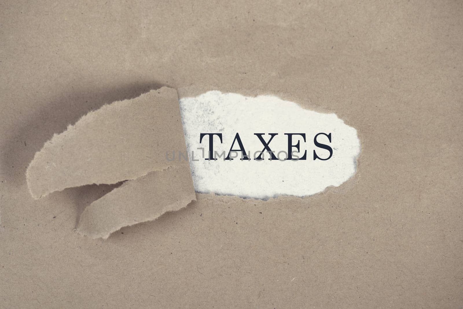 The word taxes is standing ona white background, ripped textured paper