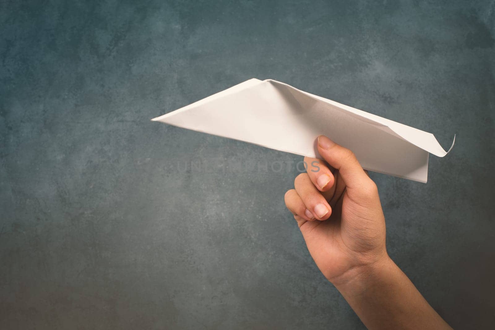 Holding a aper airplane in the handon a textured background, empty copy space for text